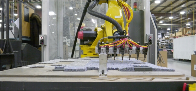 A robot applies glue to an automotive interior trim part.