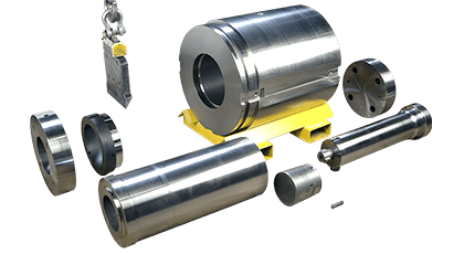 Aluminum extrusion press tooling set, including a container on a yellow pallet, a stem, and related components.